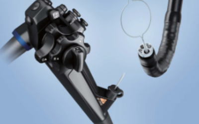 Close-up of dental implant surgical drill and handpiece against a blue background in a dental setup.