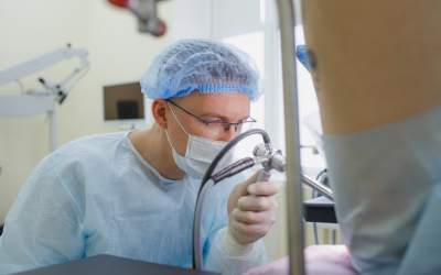 Â___digital rectal examination dre | dr. Vipulroy rathod | dr. Vipulroy rathod Surgeon in scrubs and a mask performing a procedure in an operating room, using a medical instrument.