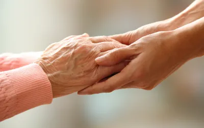 Age | dr. Vipulroy rathod | dr. Vipulroy rathod Close-up of an elderly hand being held by a younger hand in a comforting gesture.